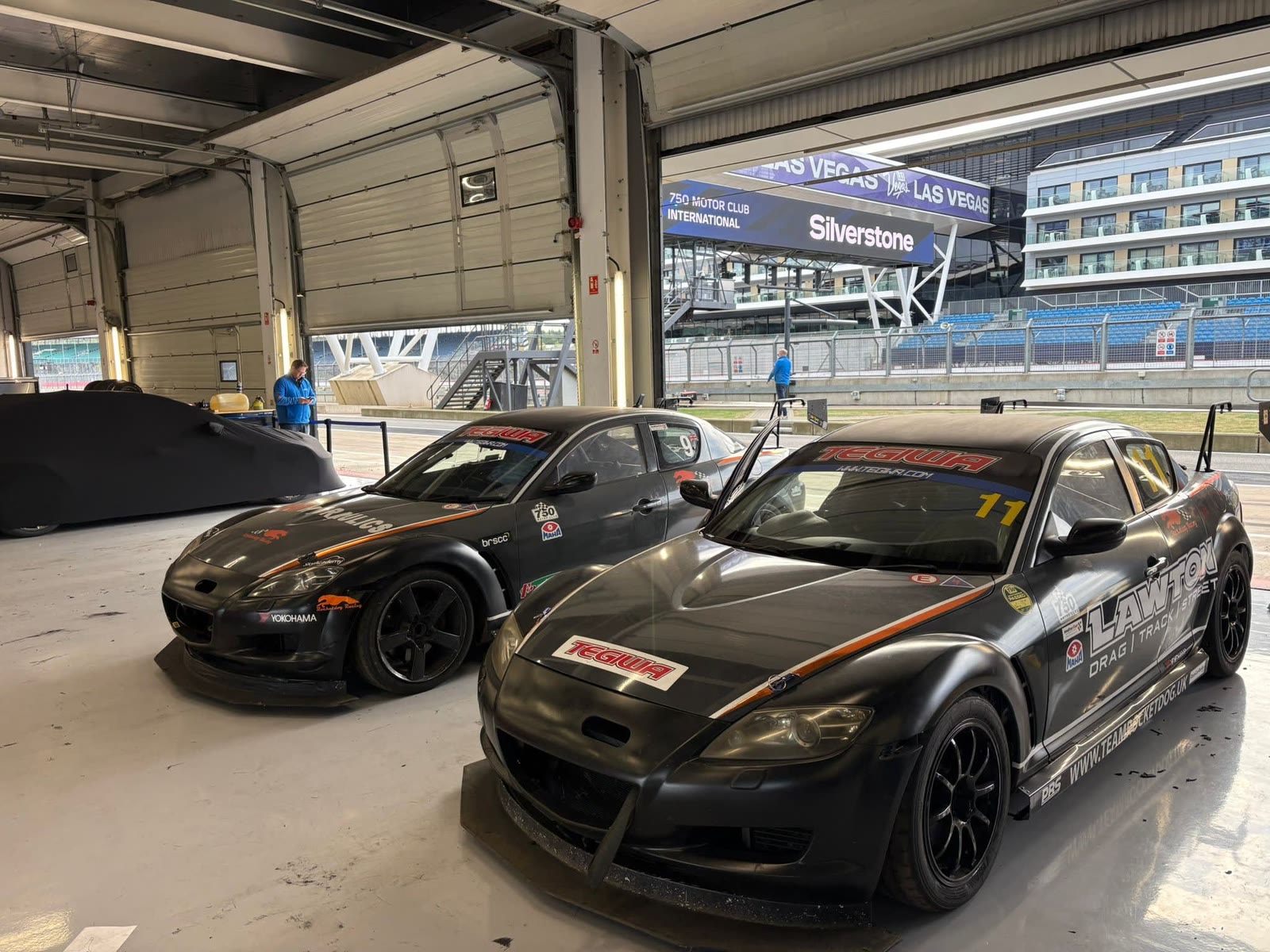 Two black Rocketdog Racing Mazda RX-8 race cars prepared in a Silverstone garage