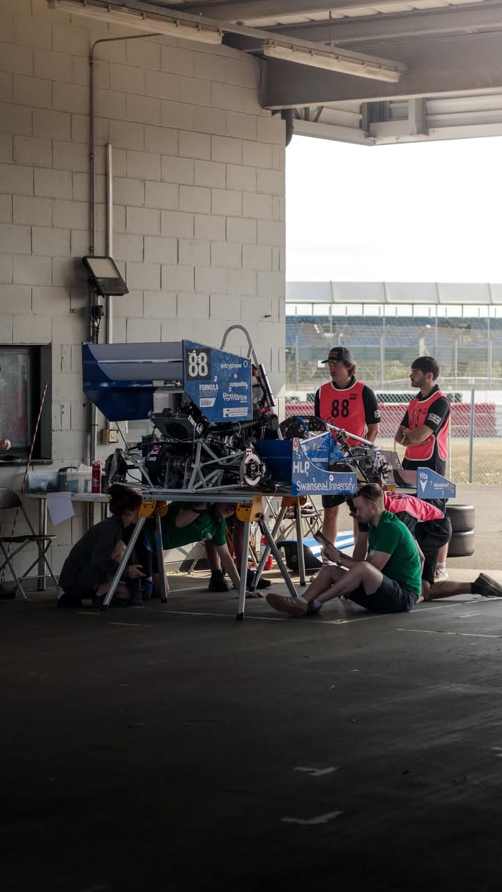 Swansea University Race Engineering students working around the rear of their Formula Student car in a Silverstone garage